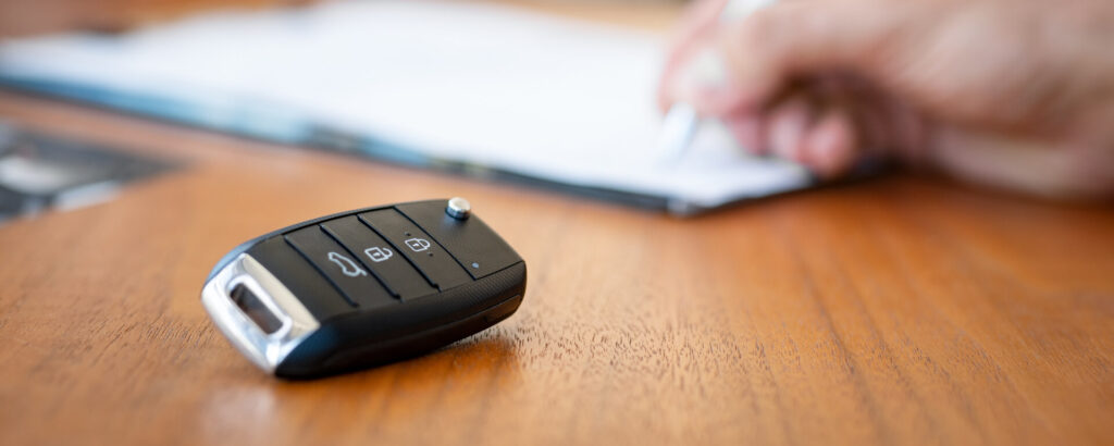 Car keys on a table next to a car insurance policy that has been voided