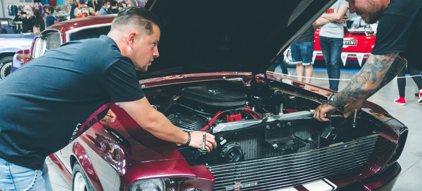 Two men working over an open car bonnet