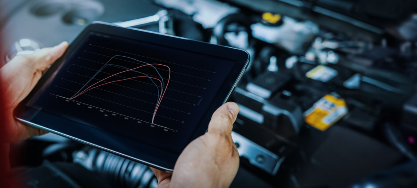 Person holding a tablet device tuning a car